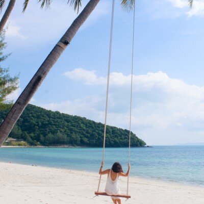 woman wearing white dress sitting on the swing